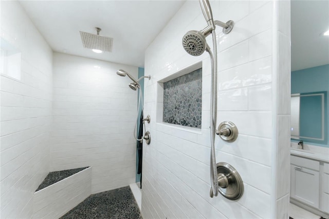 bathroom featuring tiled shower and vanity