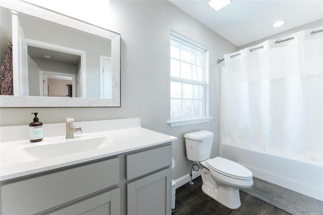 bathroom featuring baseboards, toilet, shower / tub combo with curtain, wood finished floors, and vanity