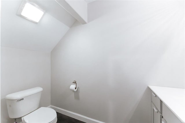 bathroom featuring lofted ceiling, vanity, toilet, and baseboards