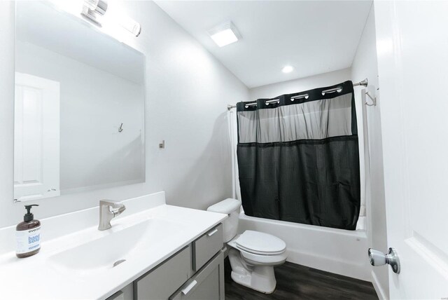 bathroom with vanity, wood finished floors, toilet, and shower / bathtub combination with curtain