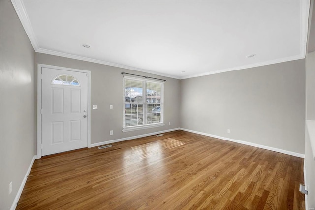 entrance foyer with ornamental molding, visible vents, baseboards, and wood finished floors