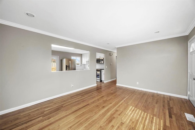 unfurnished living room with ornamental molding, visible vents, baseboards, and wood finished floors