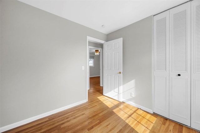 unfurnished bedroom featuring a closet, light wood-style flooring, and baseboards