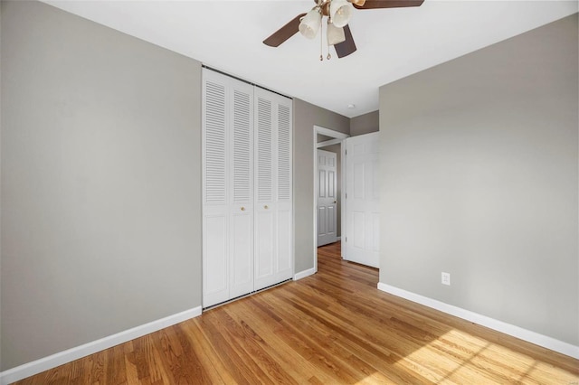 unfurnished bedroom featuring light wood-style floors, a ceiling fan, baseboards, and a closet