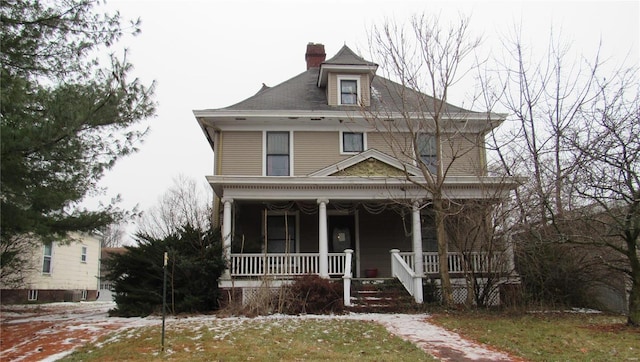 view of front of house featuring a chimney and a porch