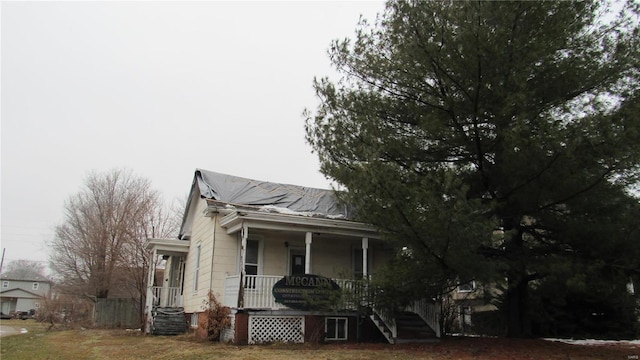 view of front facade with covered porch, fence, and a front lawn