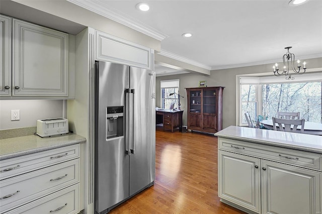 kitchen with a notable chandelier, high end fridge, hanging light fixtures, light countertops, and crown molding