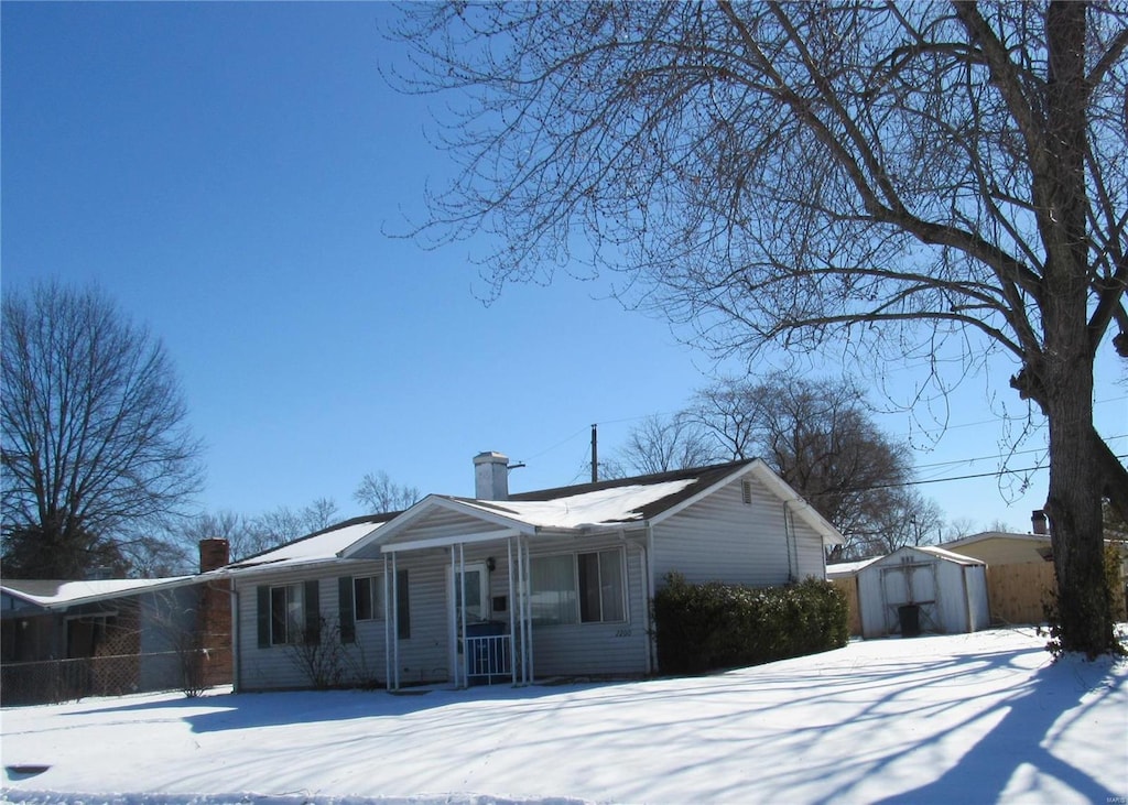 view of snowy exterior with a shed and an outbuilding