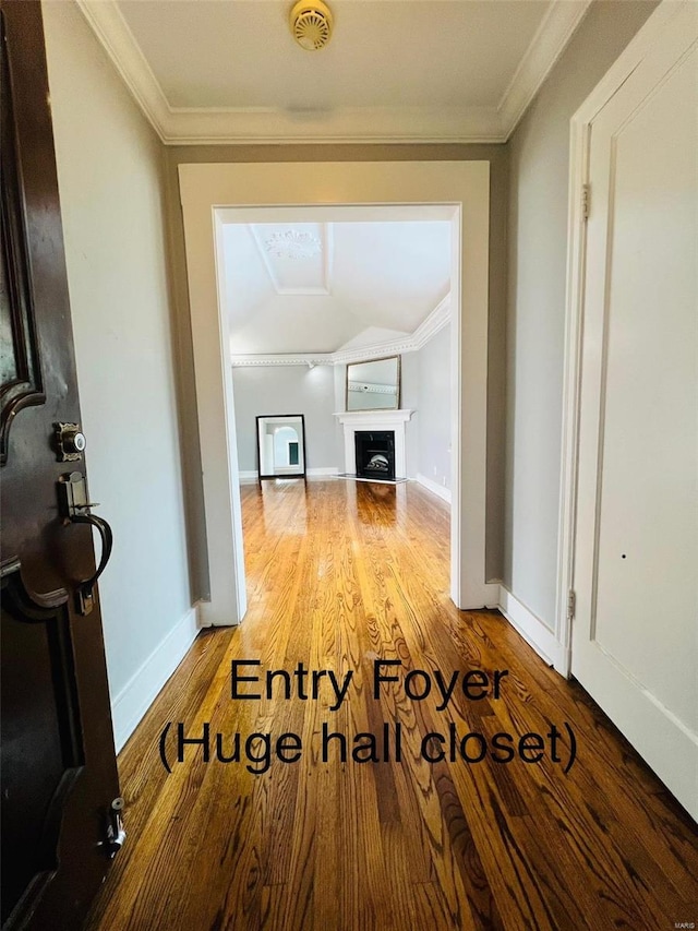 corridor with ornamental molding, baseboards, and wood finished floors