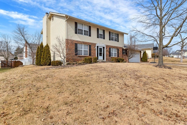 colonial home featuring a front yard, brick siding, fence, and an attached garage