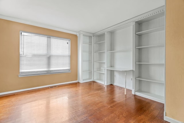 unfurnished room with visible vents, crown molding, baseboards, and wood finished floors