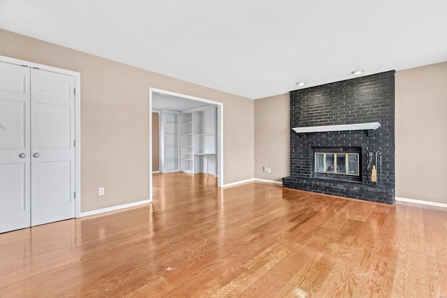 unfurnished living room with a fireplace, baseboards, and wood finished floors