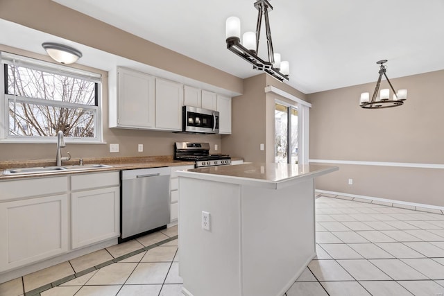 kitchen with hanging light fixtures, appliances with stainless steel finishes, white cabinets, a sink, and a kitchen island