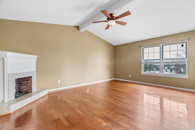 unfurnished living room with ceiling fan, lofted ceiling with beams, baseboards, light wood-style floors, and a tiled fireplace