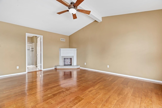 unfurnished living room with baseboards, visible vents, a fireplace with raised hearth, and wood finished floors