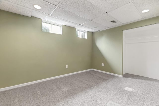 basement featuring carpet floors, baseboards, visible vents, and a paneled ceiling