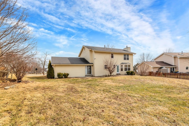 rear view of property with a lawn, a chimney, and fence