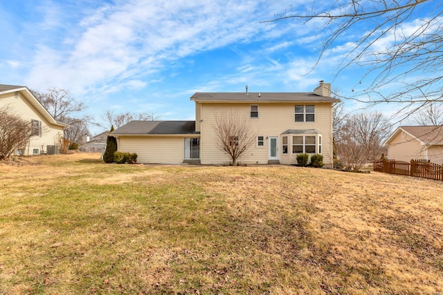 back of property with a lawn, a chimney, and fence