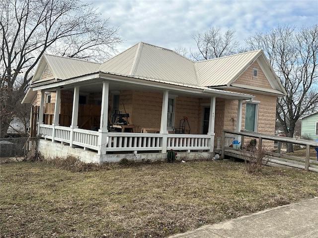 view of home's exterior featuring metal roof, a porch, and a yard