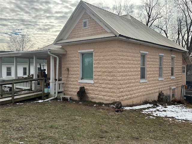 view of side of home featuring metal roof and a yard