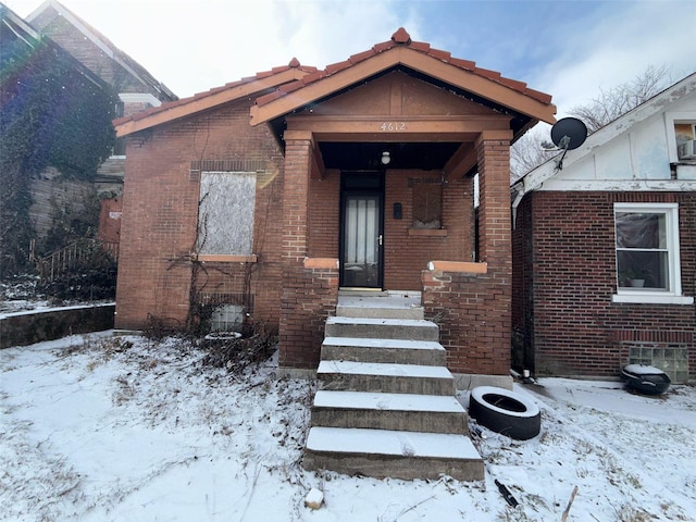 bungalow-style home with brick siding and a tile roof