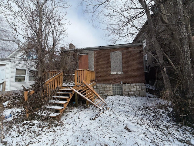 snow covered property featuring brick siding