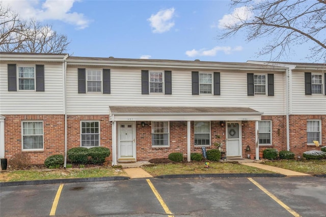 view of property featuring brick siding and uncovered parking