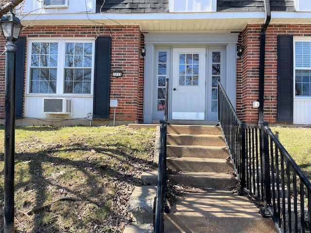 doorway to property featuring brick siding, a shingled roof, and a wall mounted air conditioner