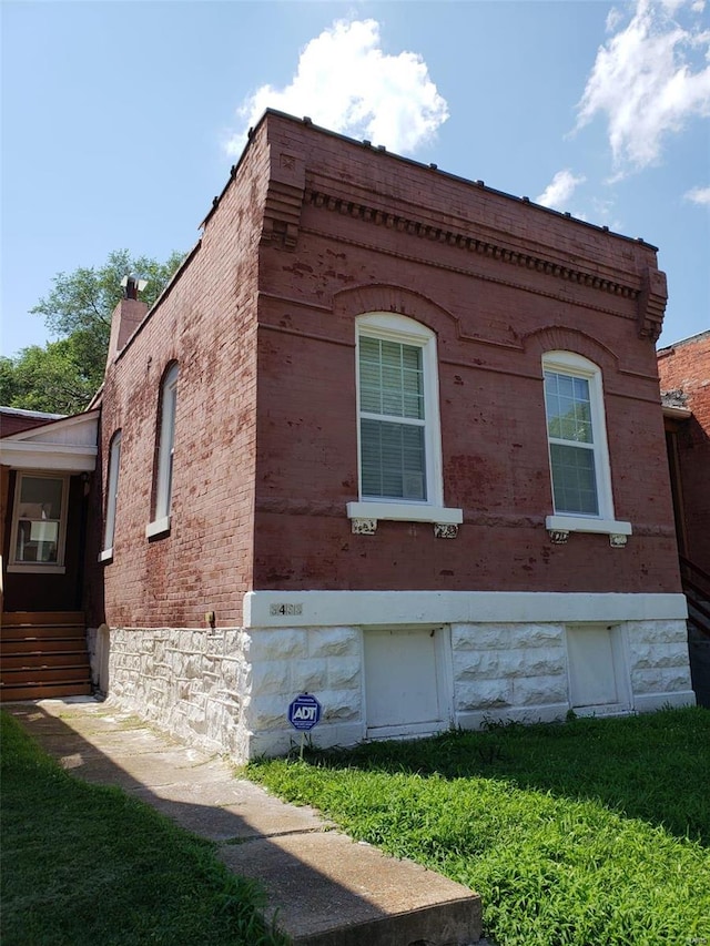 view of side of home featuring brick siding and a lawn