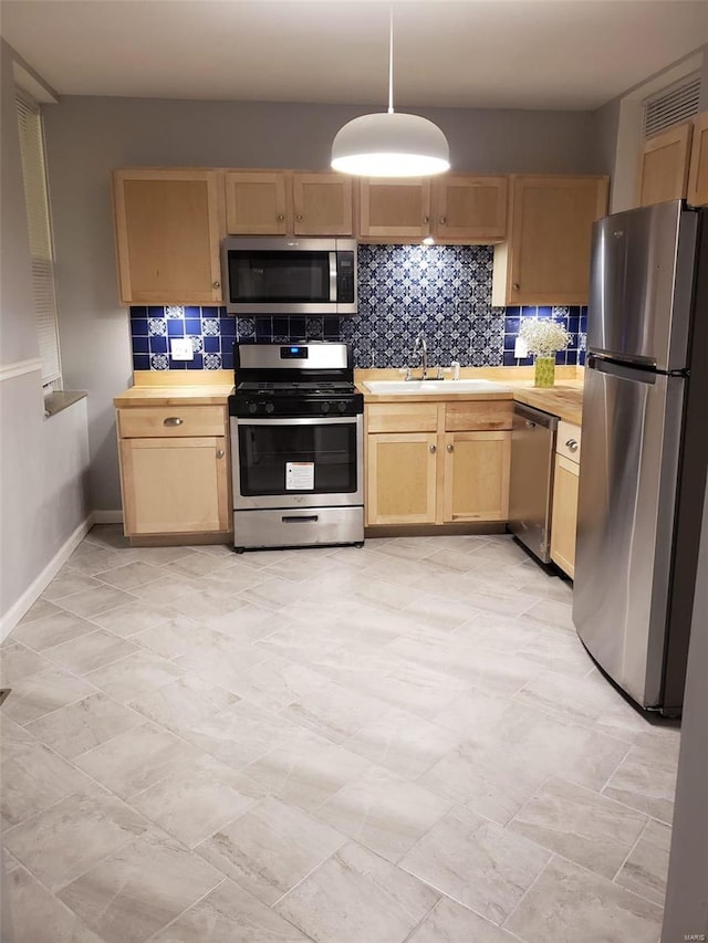 kitchen featuring backsplash, hanging light fixtures, stainless steel appliances, wooden counters, and a sink