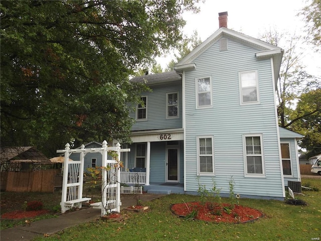 view of front of home featuring a porch, a chimney, and a front lawn