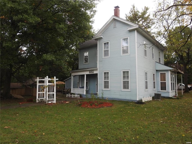 rear view of house with central AC, a lawn, and a chimney