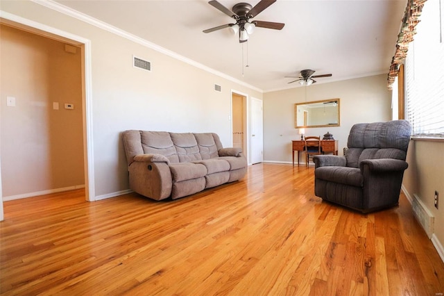 living area featuring light wood-style floors, visible vents, and crown molding