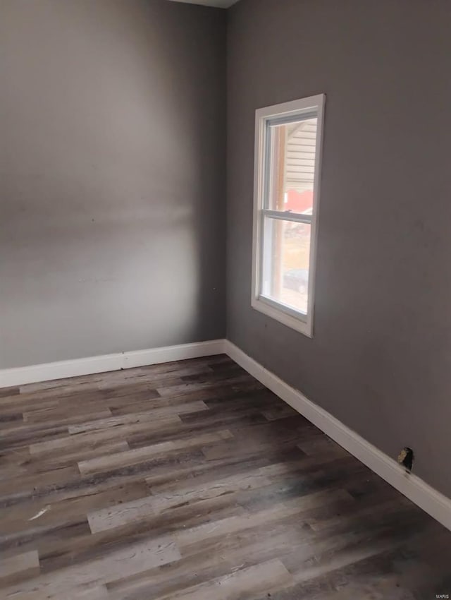 spare room with dark wood-type flooring and baseboards