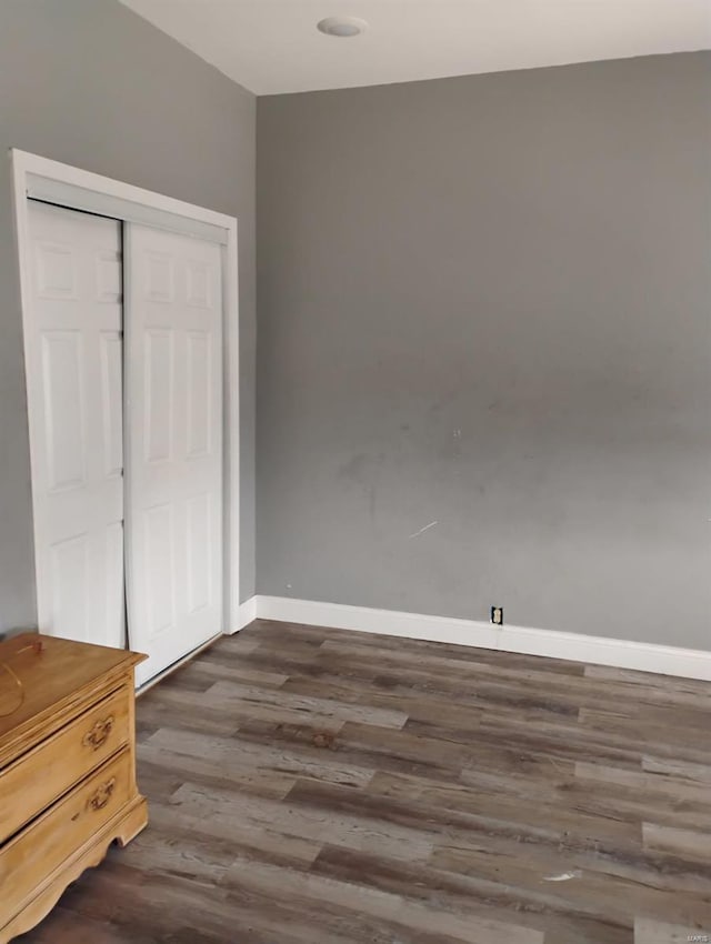 bedroom with dark wood-style floors, a closet, and baseboards