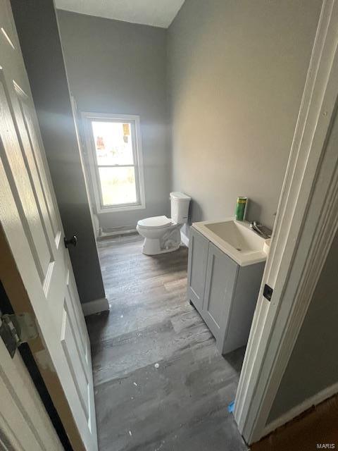 bathroom featuring vanity, wood finished floors, toilet, and baseboards