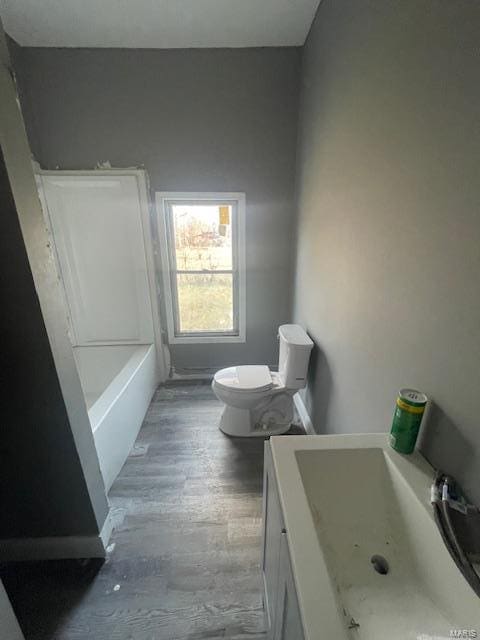 bathroom with a tub to relax in, toilet, wood finished floors, vanity, and walk in shower