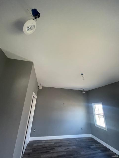 unfurnished room featuring dark wood-type flooring and baseboards