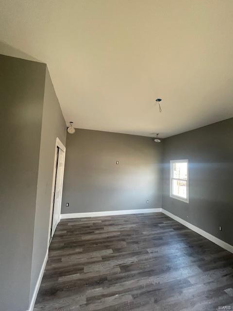 empty room featuring dark wood-type flooring and baseboards