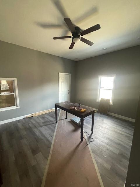 interior space featuring a ceiling fan, baseboards, and wood finished floors