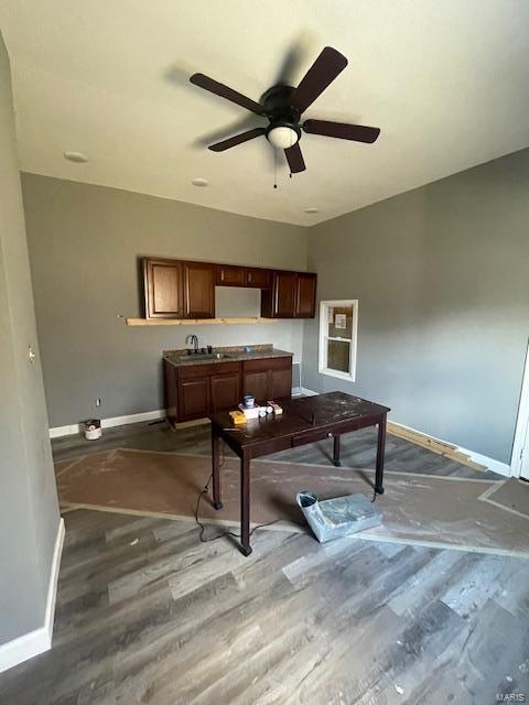 office area featuring a ceiling fan, a sink, baseboards, and wood finished floors