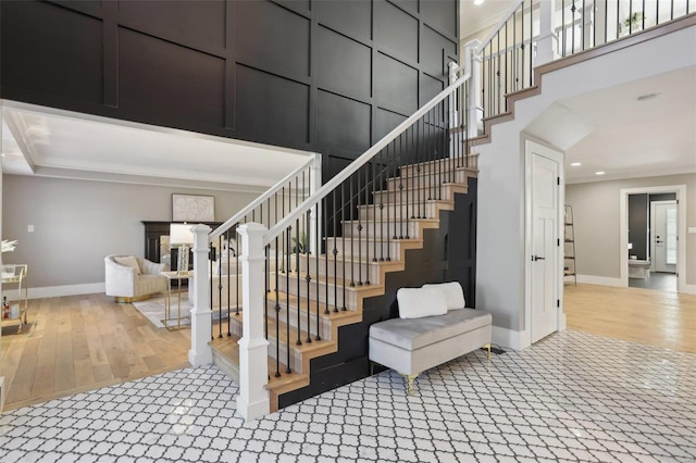 stairs featuring wood finished floors, baseboards, carpet floors, recessed lighting, and a towering ceiling