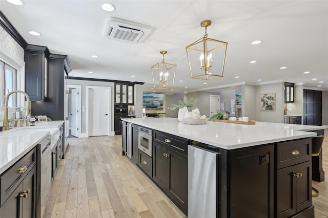 kitchen with stainless steel microwave, recessed lighting, crown molding, and light wood-style floors