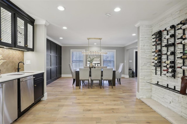 kitchen with crown molding, dishwasher, dark cabinetry, and a sink