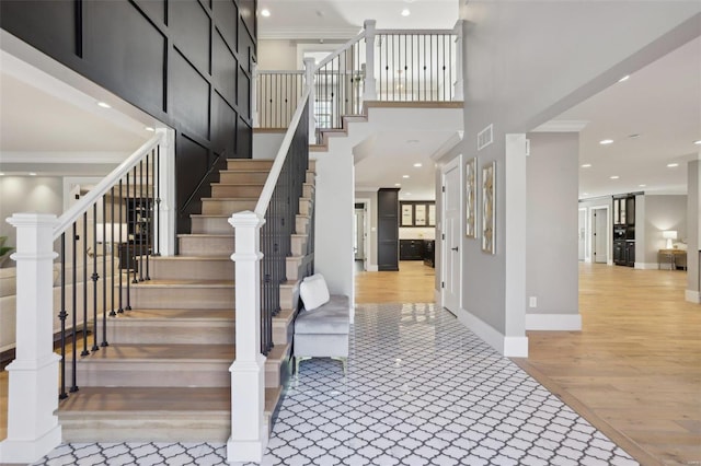 entryway featuring wood finished floors, visible vents, a high ceiling, recessed lighting, and crown molding