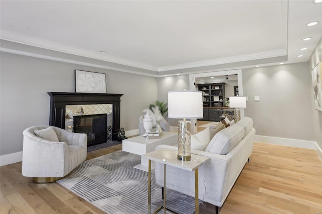 living area featuring a tiled fireplace, recessed lighting, baseboards, and wood-type flooring