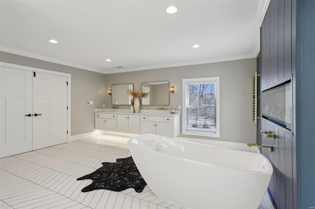 full bathroom with a soaking tub, recessed lighting, double vanity, and ornamental molding