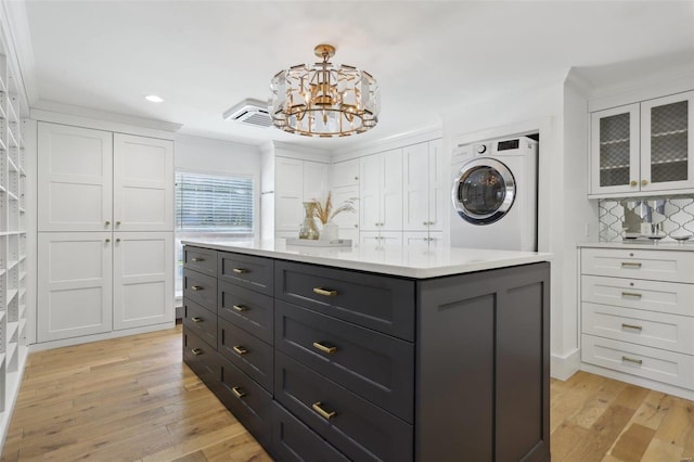 spacious closet with washer / dryer, a notable chandelier, and light wood finished floors