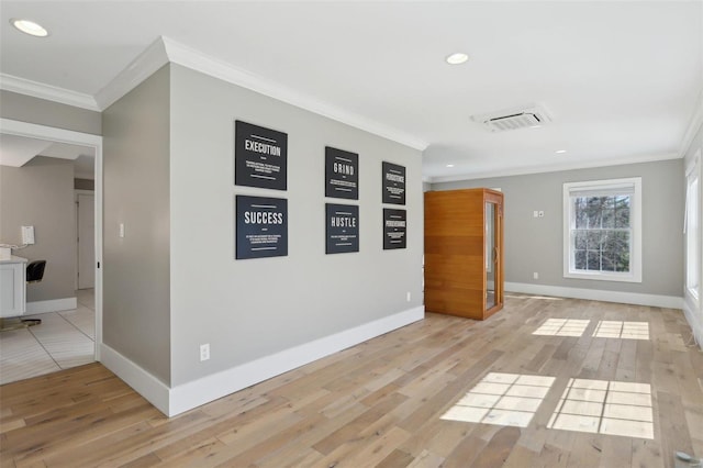 empty room with light wood-type flooring, visible vents, and ornamental molding