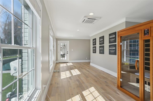 foyer featuring light wood-type flooring, visible vents, and crown molding